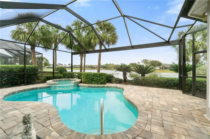 View of pool featuring a patio area, a water view, a lanai, and a pool with connected hot tub