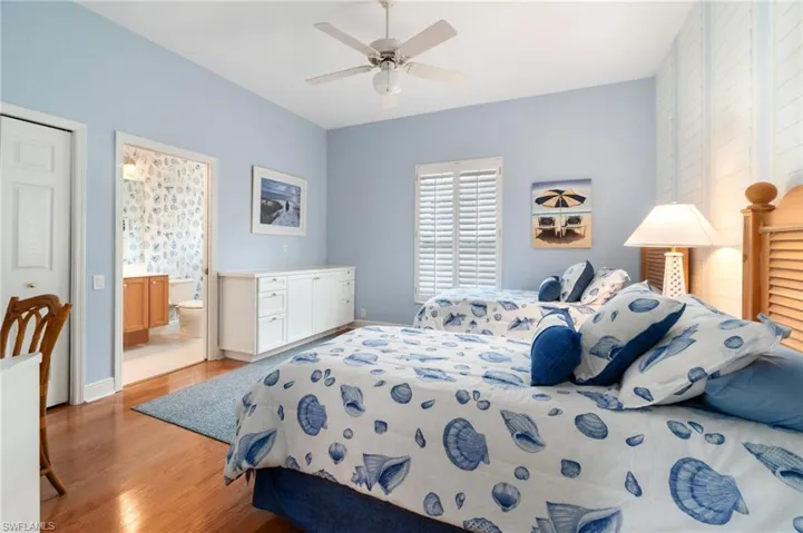 Bedroom with ensuite bathroom, ceiling fan, light wood-type flooring, and baseboards