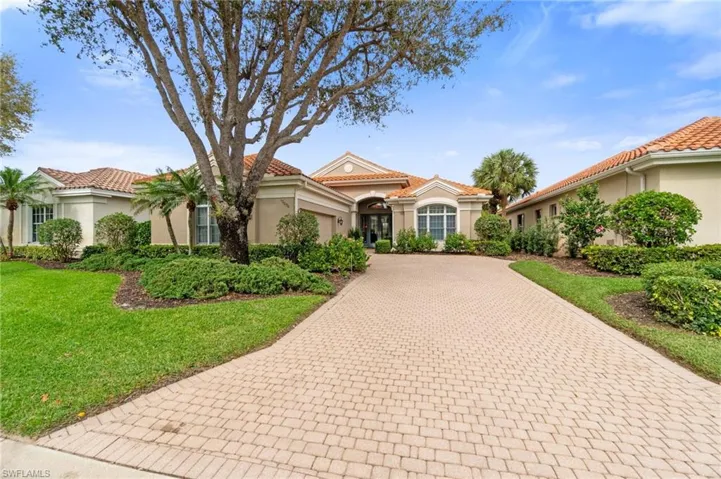 Mediterranean / spanish house with decorative driveway, a tiled roof, a front lawn, and stucco siding