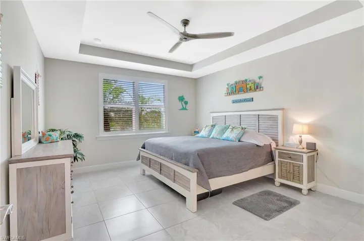 Tiled bedroom with a tray ceiling and ceiling fan