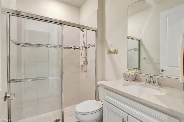Bathroom featuring toilet, vanity, and a shower with shower door