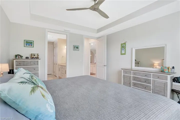 Bedroom with ceiling fan, ensuite bath, and a raised ceiling