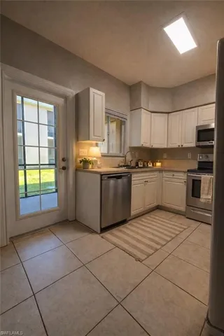 Kitchen with white cabinets, stainless steel appliances, light countertops, and light tile patterned floors