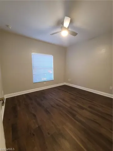 Unfurnished room with dark wood finished floors and a ceiling fan