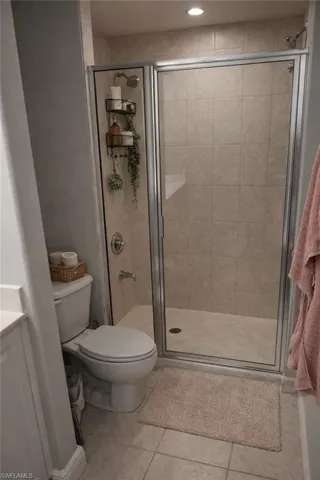 Full bathroom featuring a stall shower, vanity, and light tile patterned flooring