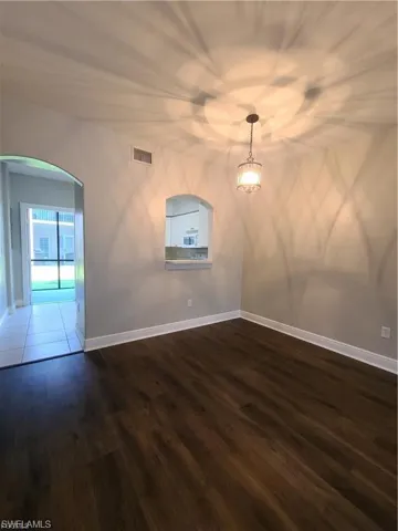 Spare room featuring arched walkways and dark wood-type flooring