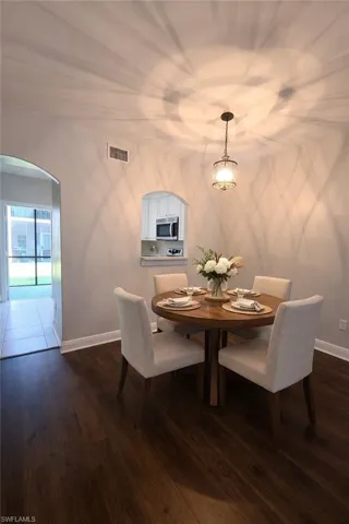 Dining room with arched walkways and dark wood-type flooring