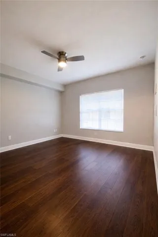 Spare room featuring dark wood-type flooring and a ceiling fan