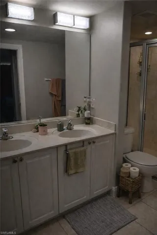Bathroom featuring double vanity, light tile patterned floors, a stall shower, and recessed lighting