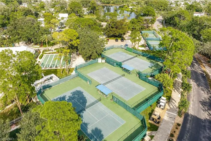 Multiple tennis courts surrounded by green fencing