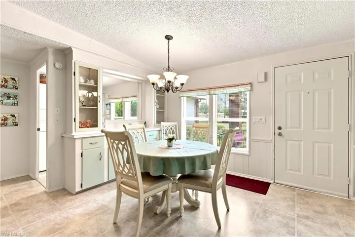 Dining area featuring tile flooring, a chandelier, and a built-in hutch with glass-front cabinetry