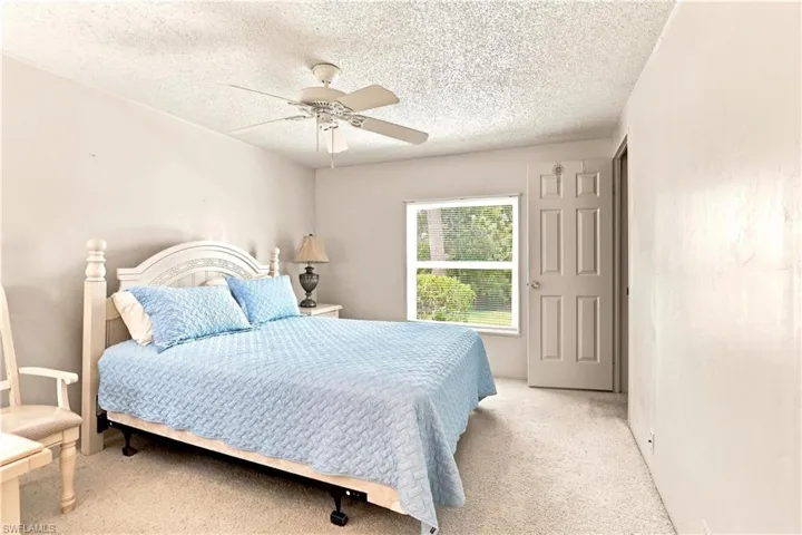 Bedroom featuring a window with exterior tree views, a ceiling fan, and carpet flooring