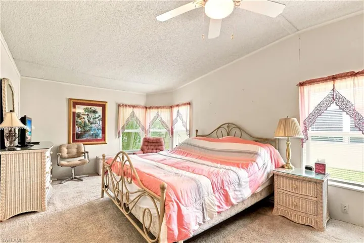 Carpeted bedroom featuring a vaulted ceiling and ceiling fan