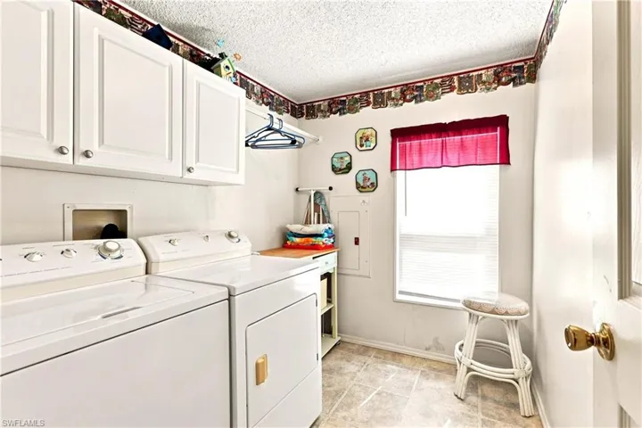 Utility room featuring white shaker-style cabinetry, a built-in hanging rod, and a window for natural light