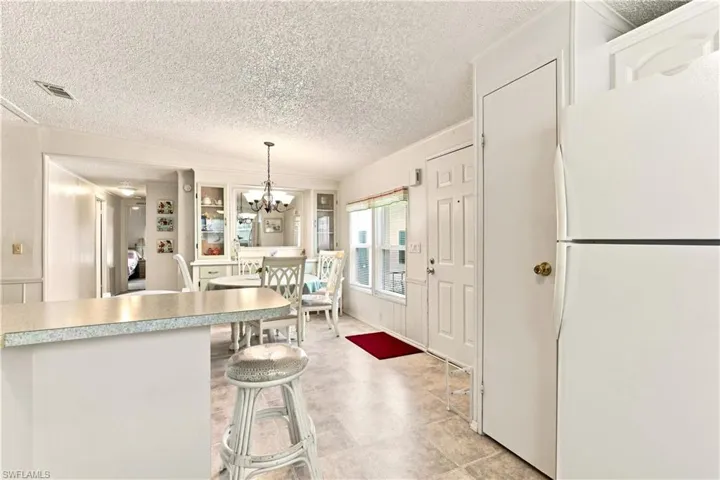 Kitchen and dining area featuring a breakfast bar, built-in display cabinetry, ceiling-mounted light fixture, and tile-finish flooring