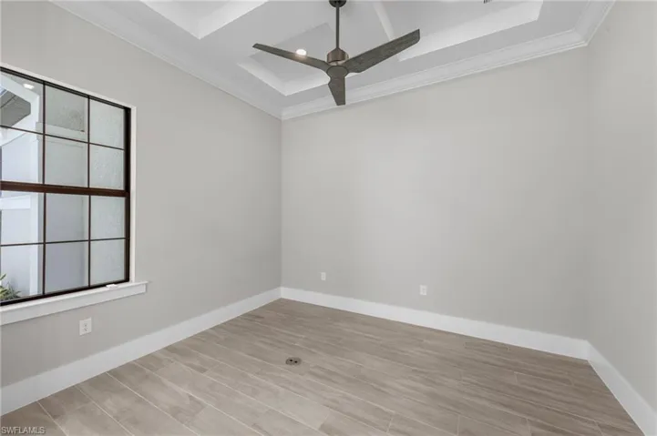 Spare room featuring coffered ceiling, wood tiled floors, ornamental molding, a ceiling fan, and beamed ceiling