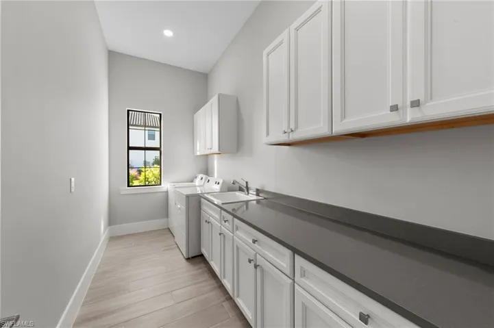 Laundry area with cabinet space, washer and clothes dryer, light wood-type flooring, and recessed lighting