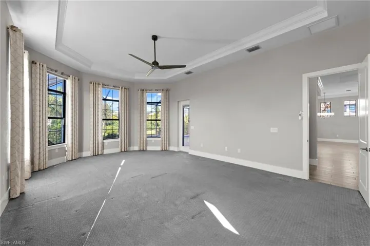 Carpeted empty room featuring a raised ceiling and ceiling fan