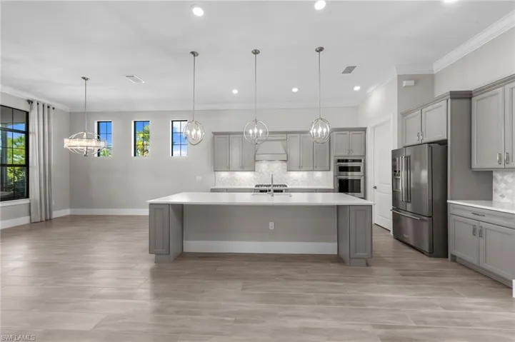 Kitchen featuring gray cabinetry, ornamental molding, stainless steel appliances, hanging light fixtures, and custom range hood