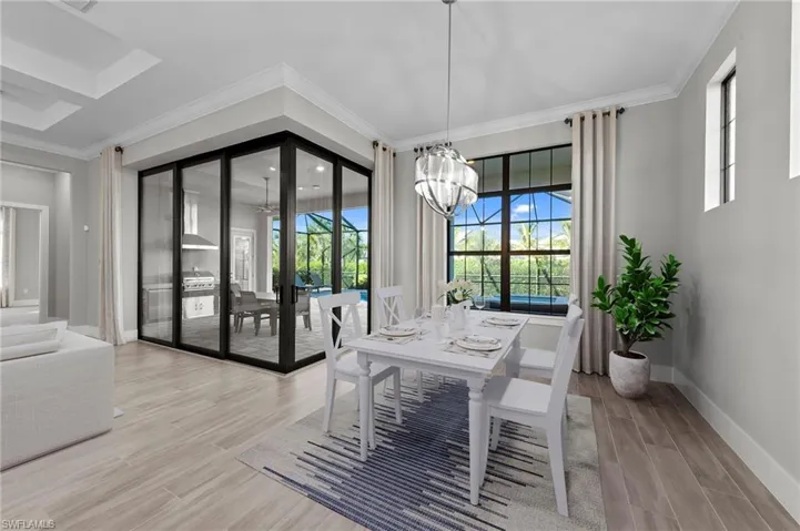 Dining space featuring crown molding, light wood-style floors, healthy amount of natural light, and a chandelier
