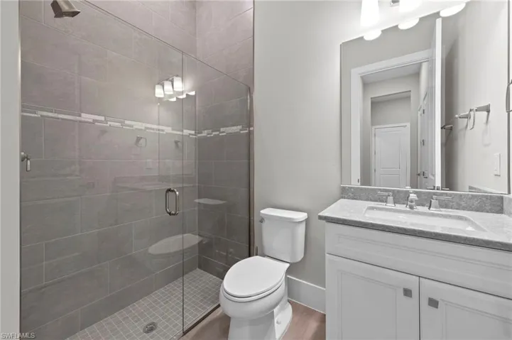 Full bathroom featuring vanity, a stall shower, and wood finished floors
