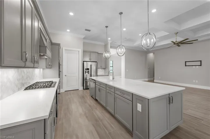 Kitchen featuring gray cabinets, backsplash, pendant lighting, a ceiling fan, and light wood-type flooring