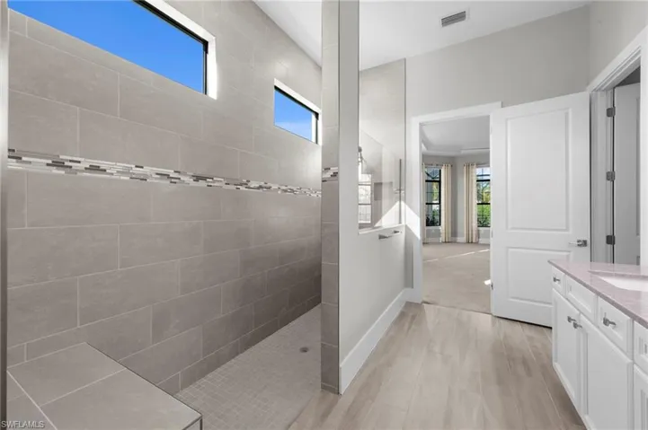 Bathroom featuring healthy amount of natural light, walk in shower, and vanity