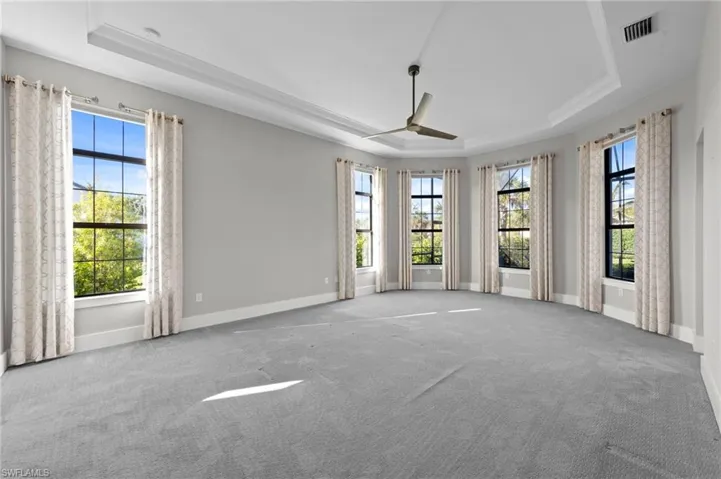 Carpeted empty room with a tray ceiling and a ceiling fan