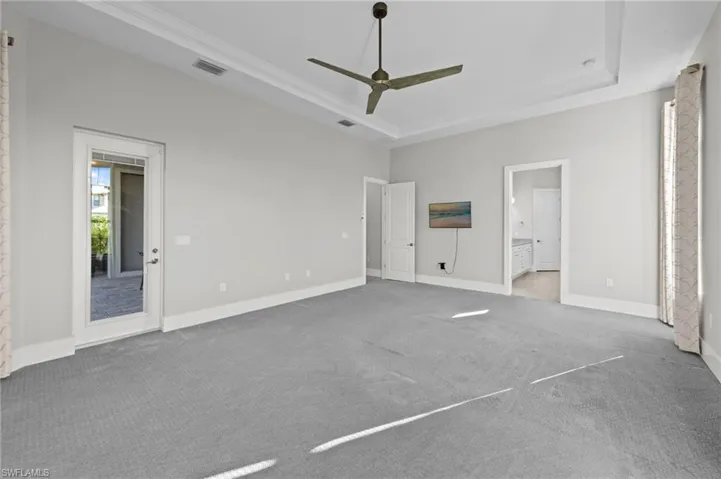 Unfurnished bedroom with a raised ceiling, a ceiling fan, carpet flooring, and connected bathroom