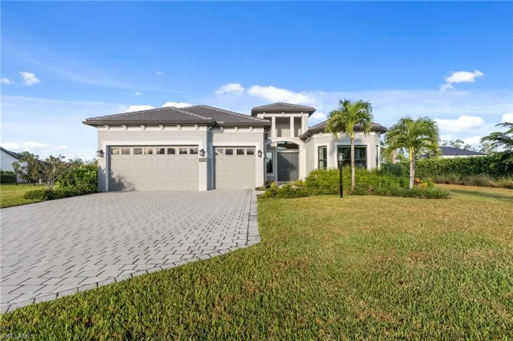 Prairie-style home with stucco siding, a garage, a front lawn, and decorative driveway
