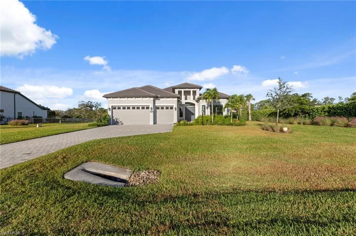 View of front of property featuring a front yard, an attached garage, and decorative driveway