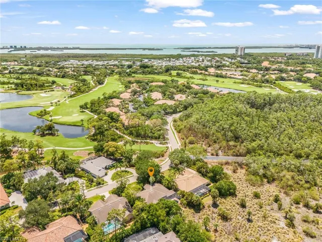 Aerial perspective 2nd home from the end showcasing a  residential property amidst lush landscaping, golf course fairways, and distant bodies of water