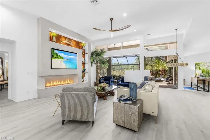Spacious living area featuring light wood-finish tile flooring, a contemporary fireplace and vaulted ceilings