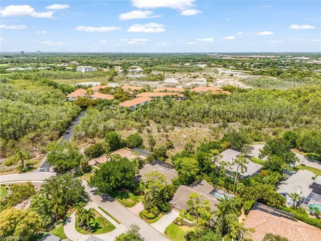 Aerial perspective showcasing a residential community surrounded by abundant mature trees and natural landscaping