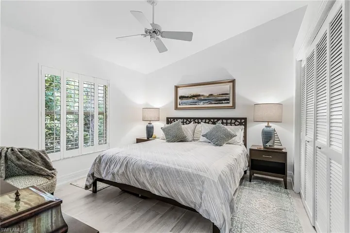 Guest Bedroom  2 featuring wood-finish flooring, white louvered bifold closet doors, a white ceiling fan, and window shutters