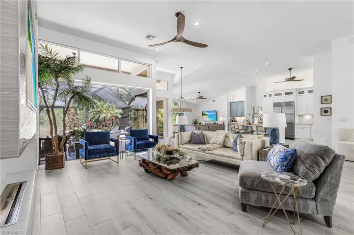 Spacious interior featuring high vaulted ceilings, large format tile flooring, and extensive window walls overlooking a screened outdoor area
