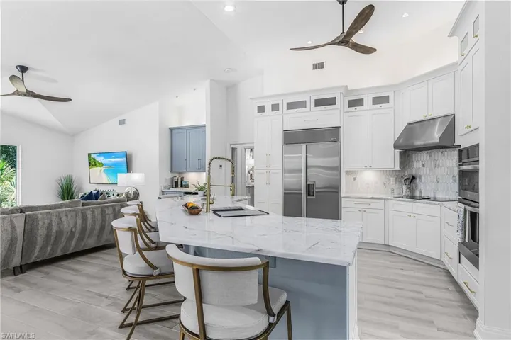 Spacious kitchen featuring white cabinetry, a large center island with a marble-finish countertop, a stainless steel Sub-Zero  refrigerator, and integrated convection  oven & microwave