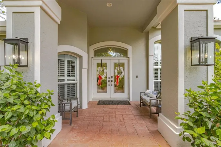 Entryway featuring a stamped concrete porch, dual glass-paneled doors with an arched transom, and symmetrical exterior sconces
