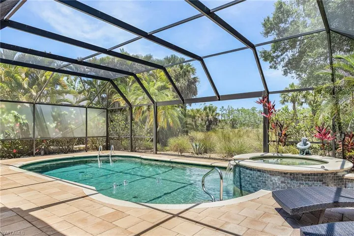 Screened lanai featuring an in-ground pool and integrated spa with a waterfall feature