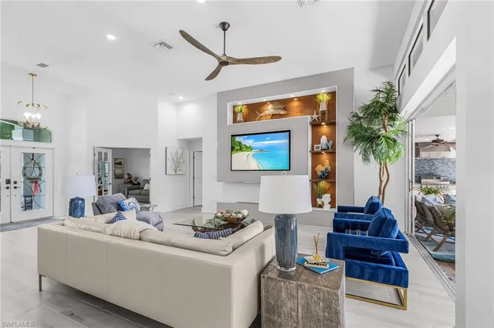 Spacious living area featuring high ceilings, light-toned flooring, and a contemporary ceiling fan