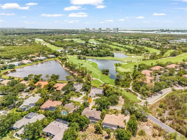 Aerial perspective showcasing a residential community surrounded by lush golf course greens and water features