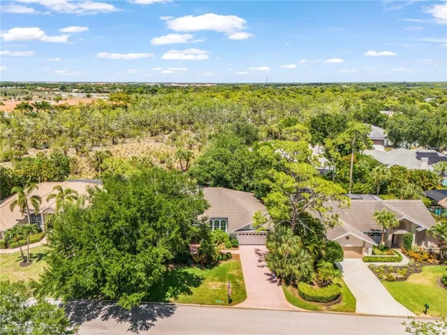 Property featuring a tile roof, an integrated two-car garage, mature landscaping, and a paver driveway