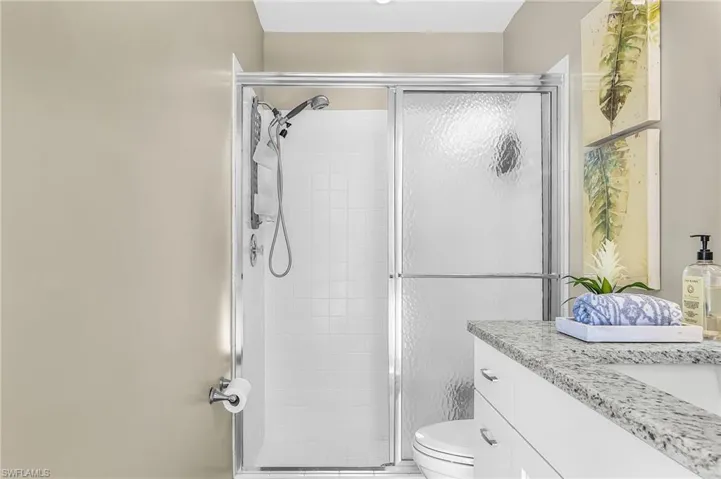 Pool Bathroom with granite vanity and white tile floor and shower