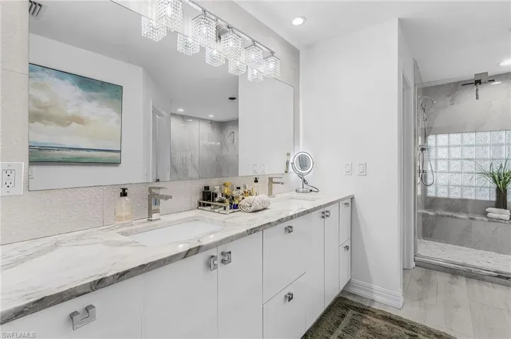Dual vanity with stone countertop and integrated sinks, complemented by a large mirror and contemporary lighting