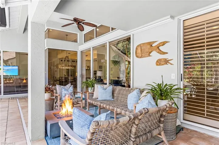 Covered lanai area featuring a ceiling fan, a fire pit, and glass sliding doors with transoms