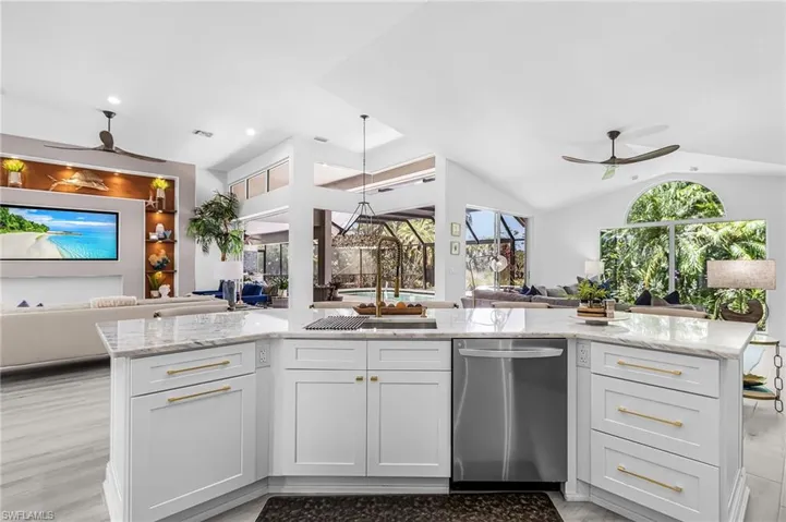 Gourmet kitchen island with white cabinetry, gold hardware, and stone countertops