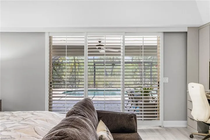 Sliding glass doors with plantation shutters open to an outdoor lanai with a swimming pool & spa