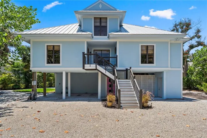Beach home with a metal roof, a carport, driveway, and stucco siding