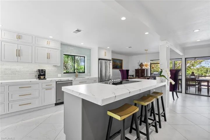 Kitchen featuring backsplash, a kitchen bar, decorative light fixtures, recessed lighting, and light stone counters