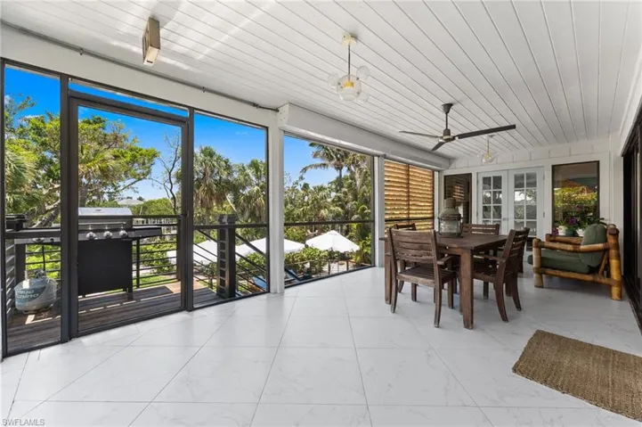Sunroom / solarium featuring marble look tile flooring, ceiling fan, outdoor dining area, and wood ceiling